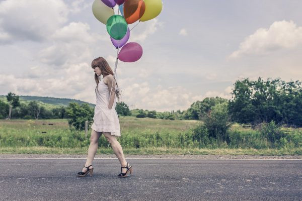 Девушка с воздушными шарами идет по улице