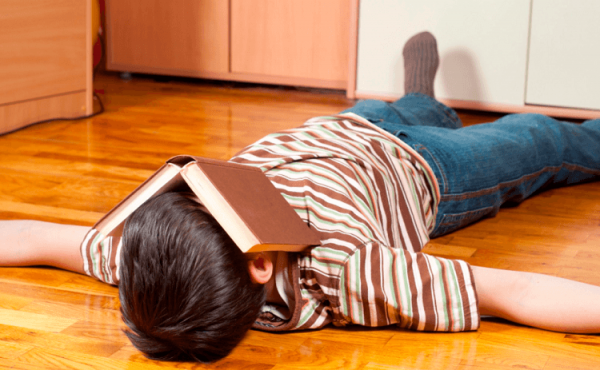 Мальчик лежит на полу с книгой на голове