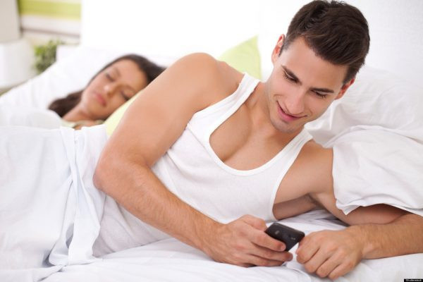 Мужчина с телефоном лежит на кровати