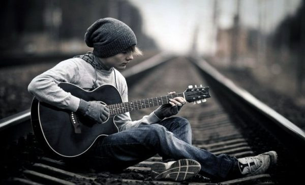 Мальчик с гитарой на железнодорожных путях