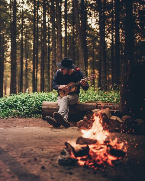 Лесной мальчик играет на укулеле у костра