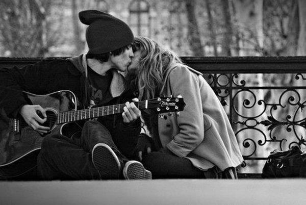 Молодой человек с гитарой целует девушку