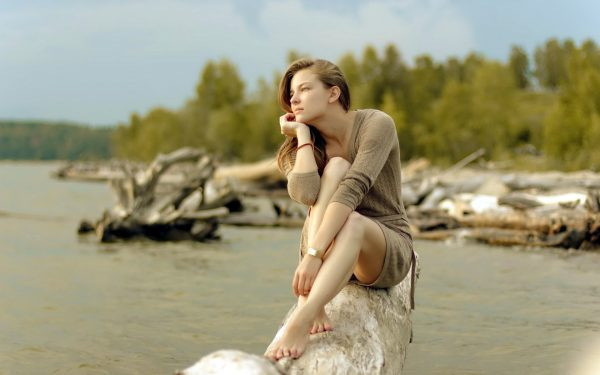 Девушка сидит на пляже и медитирует