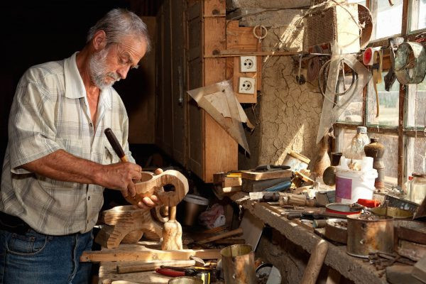 Мужчина вырезает деревянные фигуры