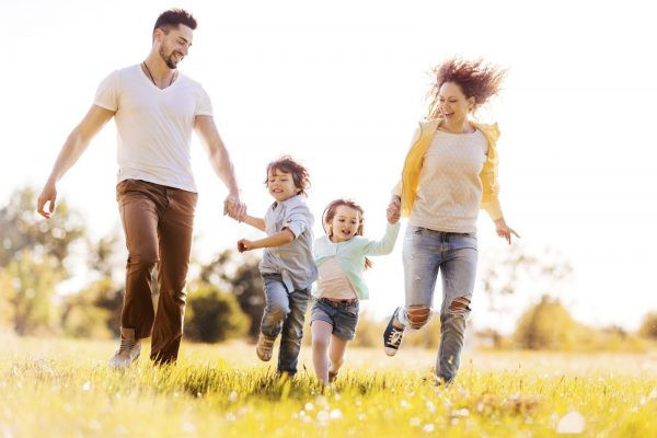 Жена, муж и дети бегают по траве